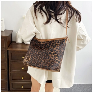 Dettaglio della borsa tote leopardata con spalline marroni indossata in un interno accogliente