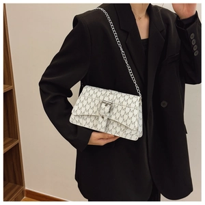 Dettaglio della borsa monogramma bianca con catena d'argento sulla spalla del modello