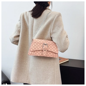 Dettaglio borsa a spalla beige vintage con motivo a M e tracolla a catena argento