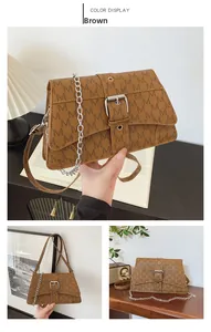 Detail of brown PU leather crossbody bag with M-pattern, silver chain, and buckle closure