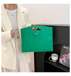 Détail du sac cabas en cuir vert grainé avec poignées découpées et fermeture aimantée
