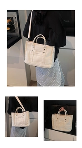 Detail of cream canvas tote bag showing metal rivets, front pocket, and adjustable strap