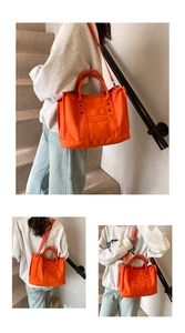 Orange canvas tote bag worn by a model in hand-held and cross-body styles