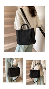 Detail view of the black canvas tote bag showing stitching and detachable shoulder strap