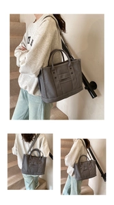 Detail of gray canvas tote bag featuring cylindrical handles and adjustable fabric strap