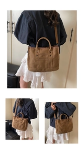 Detail view of large brown canvas tote bag with reinforced handles and adjustable strap