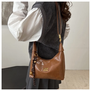 Brown leather crescent bag with gold logo shown on model for vintage stylish look