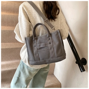 Close-up of grey canvas tote bag with reinforced handles and adjustable wide strap