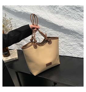 Detail of minimalist beige tote bag with brown trim and unique knot handle design