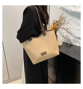 Détail d'un grand sac cabas beige avec lanières en cuir marron et étiquette de mode
