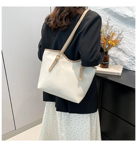 Close-up of minimalist cream leather tote bag with brown straps in a lifestyle setting