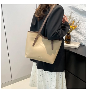 Detail of large beige tote bag with brown straps and logo print for daily commute