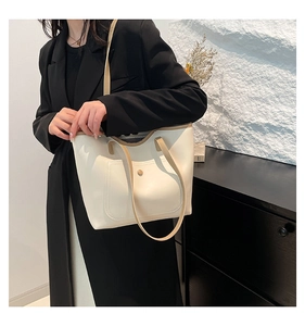 Detail of minimalist tote bag showing beige PU leather texture and light brown strap