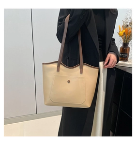 Chic beige tote bag with brown straps and exterior pocket shown in lifestyle setting