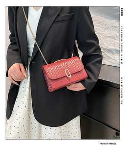 Close-up of red woven crossbody bag with gold U-shaped metal lock and chain strap