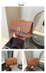 Detail of woven texture with golden oval metal lock and chain strap on brown crossbody bag