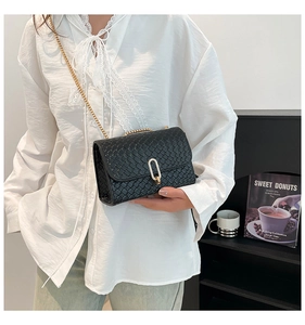 Detail of black woven texture shoulder bag with gold chain strap and metal lock