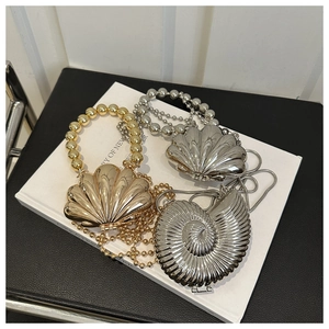 Detail of seashell-shaped metal evening bags with pearl handles and chain straps
