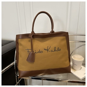 Detail of canvas tote bag with leather trim and Frida Kahlo script lettering