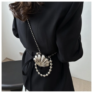 Detail of silver shell-shaped mini bag with metallic beads handle and chain strap