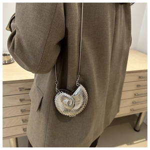 Detail shot of a silver seashell mini bag with metallic finish and delicate chain strap
