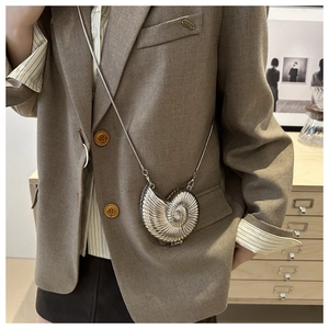 Detail of nautilus-shaped silver mini crossbody bag with sleek pearl-like metallic finish