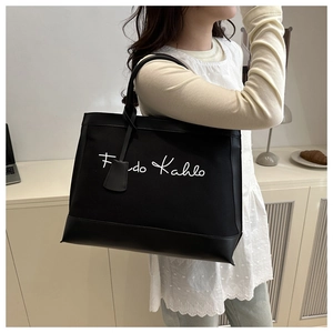 Detail of canvas tote bag with leather base and Frida Kahlo script signature