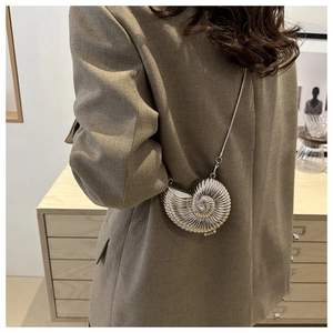 Detail of silver shell-shaped mini bag with metallic finish and delicate chain strap