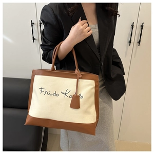 Detail of canvas tote bag with Frida Kahlo lettering and brown leather trim features