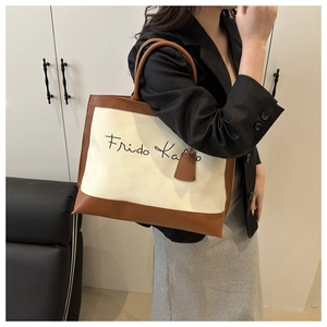 Detailed shot of Frida Kahlo script print on a beige canvas and brown leather tote bag