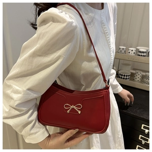 Gros plan détaillé d'un sac bandoulière rouge en cuir avec une boucle nœud dorée