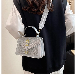 Detail of silver woven leather crossbody bag with gold buckle and geometric strap on model