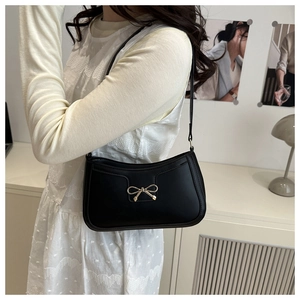Détail d'un sac sous le bras noir minimaliste avec une boucle en forme de nœud doré