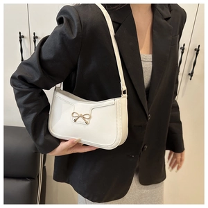 Détail du sac sous le bras en cuir blanc avec boucle décorative en nœud doré