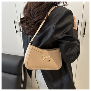 Gros plan sur le fermoir nœud doré du sac à bandoulière beige en simili cuir