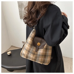 Detail of vintage plaid wool tote with brown leather flap and golden N buckle on model