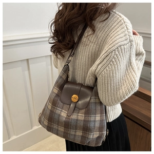 Detail of vintage plaid wool shoulder bag with brown leather flap and golden metal buckle