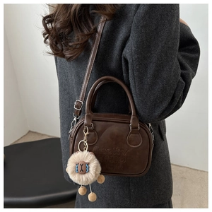 Detail der braunen PU-Ledertasche mit Lucky OHIO-Prägung und Plüsch-Anhänger