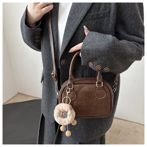 Detail der braunen Bowling-Tasche mit lucky OHIO-Prägung und flauschigem Anhänger
