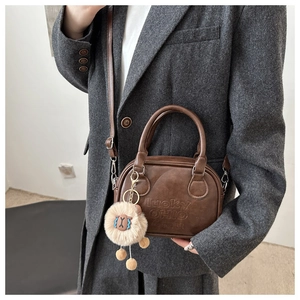 Close-up of brown vintage Boston bag with lucky OHIO embossing and alpaca charm