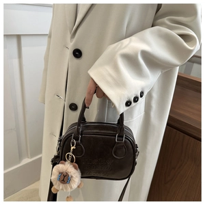 Detail of dark brown leather handbag with lucky OHIO bmu embossing and plush lion pendant