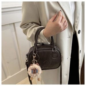 Detail of dark brown leather bowling bag with lucky OHIO amu embossed text and plush charm