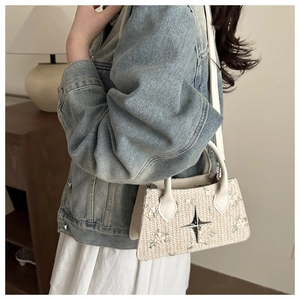 Detail of hand-woven beige bag with flower embroidery and silver star metal accessory