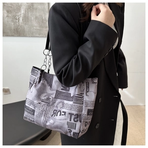 Dettaglio borsa shopper con stampa di giornale, catena argento e blazer nero
