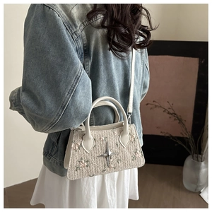 Detail of floral embroidery and star charm on woven straw handbag with crossbody strap