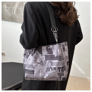 Detail of canvas tote bag featuring vintage newspaper print and metal chain shoulder strap