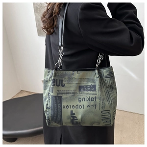 Dettaglio della borsa tote con stampa giornale rétro e catena d'argento su modella