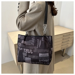 Detail of printed tote bag featuring vintage newspaper pattern and silver chain accents