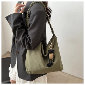Detail of olive green nylon tote bag featuring ruched strap and plush sheep charm