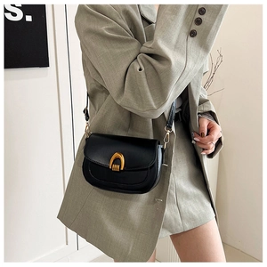 Minimalist black leather saddle bag with gold arched buckle and adjustable strap